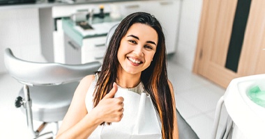 Woman smiling in dental chair with thumbs up